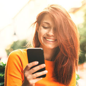 Smiling female texting on phone during a sunny day