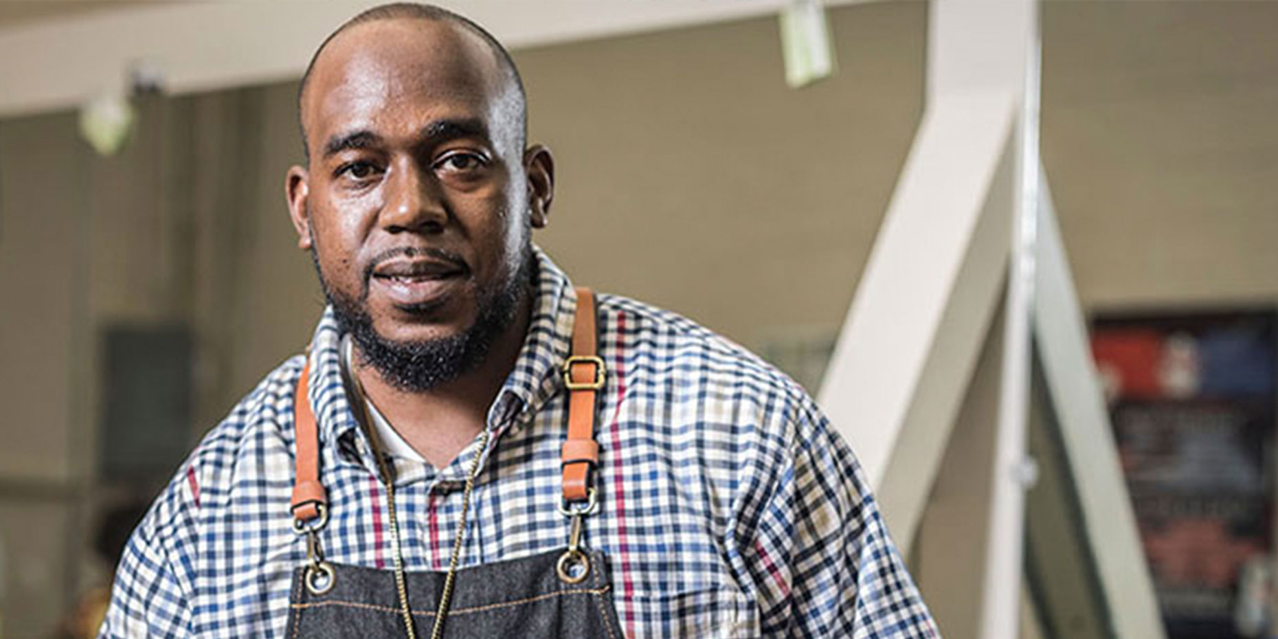 Man wearing an apron looking into the camera with a smile.