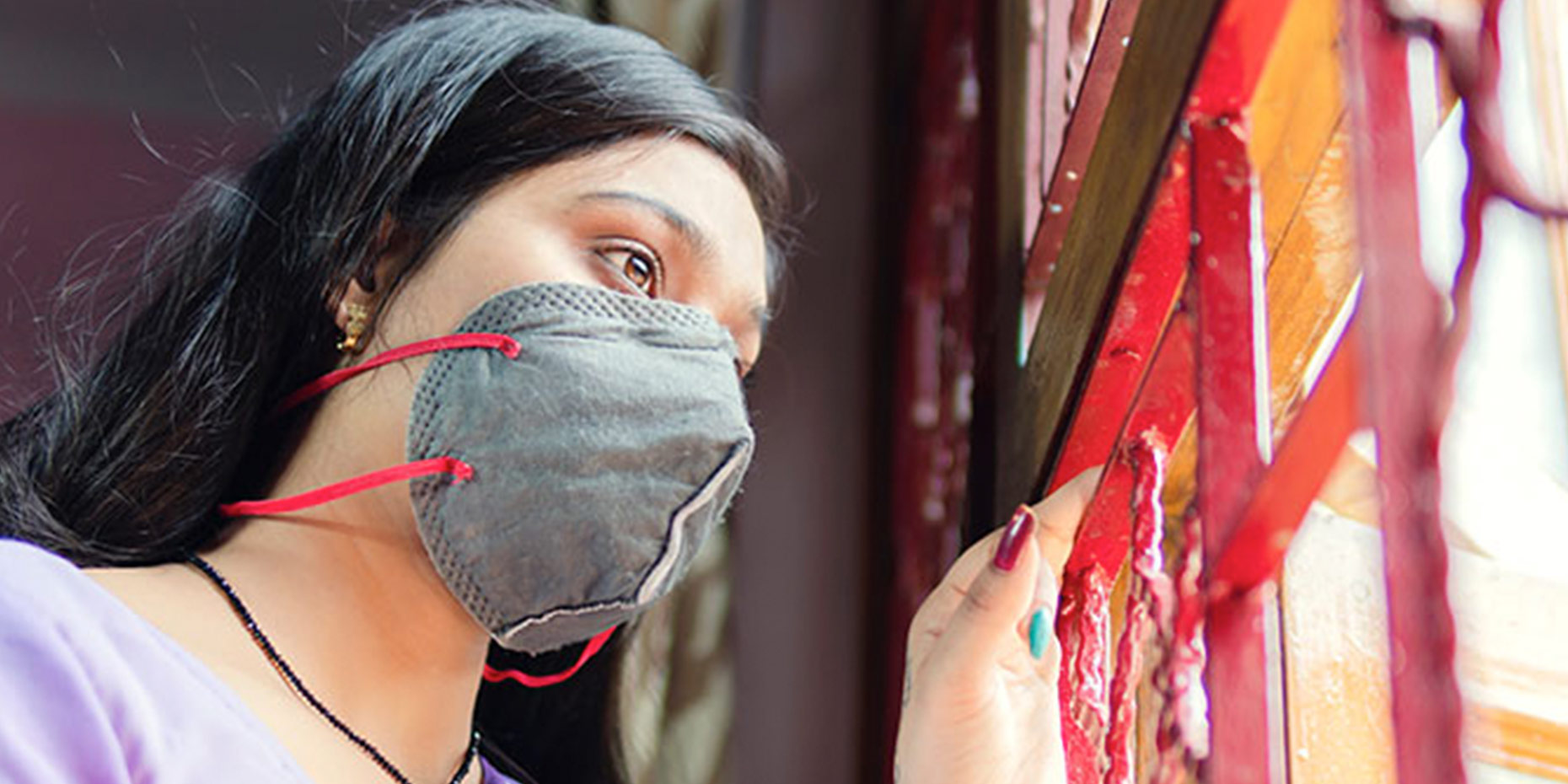 woman wearing a mask looking out the window