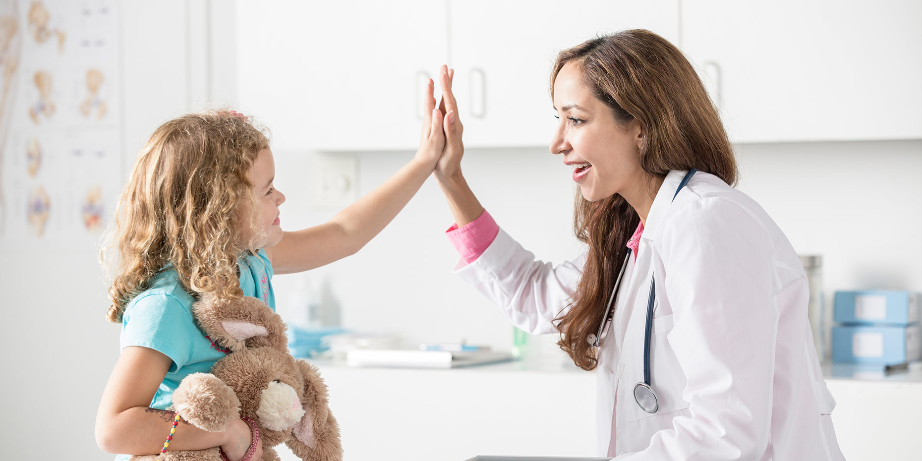 Child smiling high fiving doctor also smiling