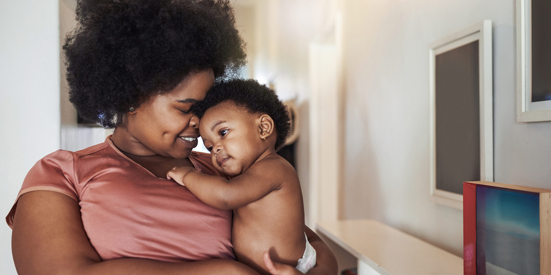 Black mom smiling nuzzling holding sweet baby resting head on mom