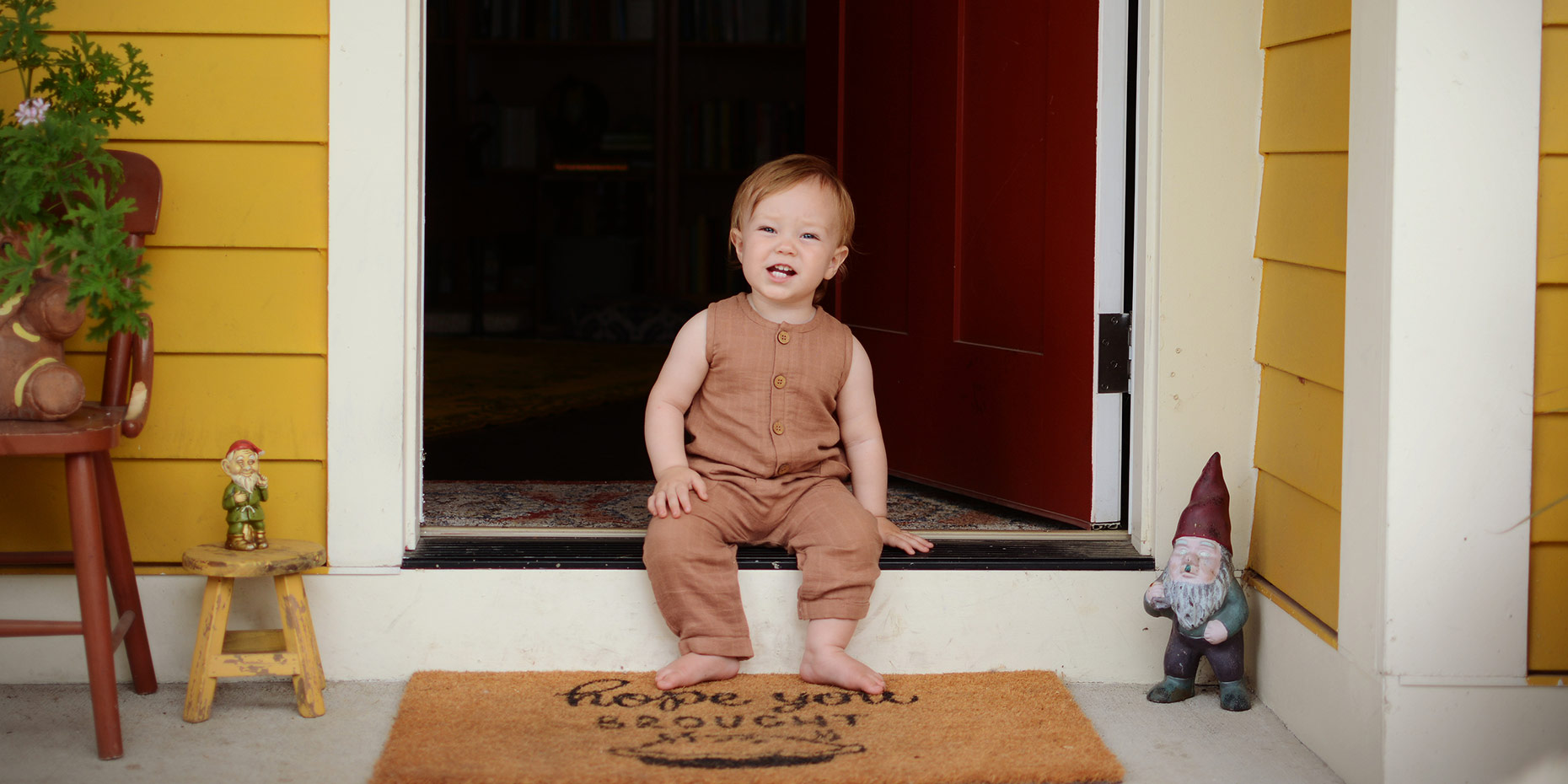 Young toddler looking past camera smiling sitting on front step of home