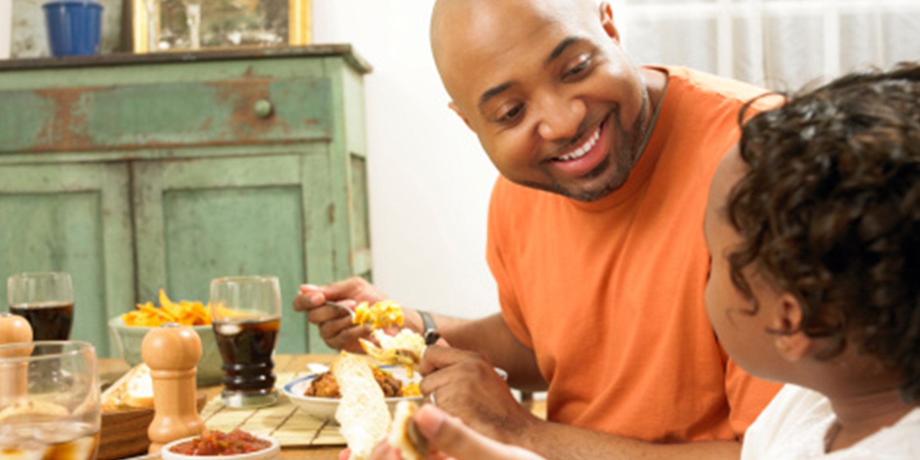 Father looking at child smiling while they eat dinner at the table