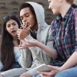 teen lighting cigarette in front of disapproving friends