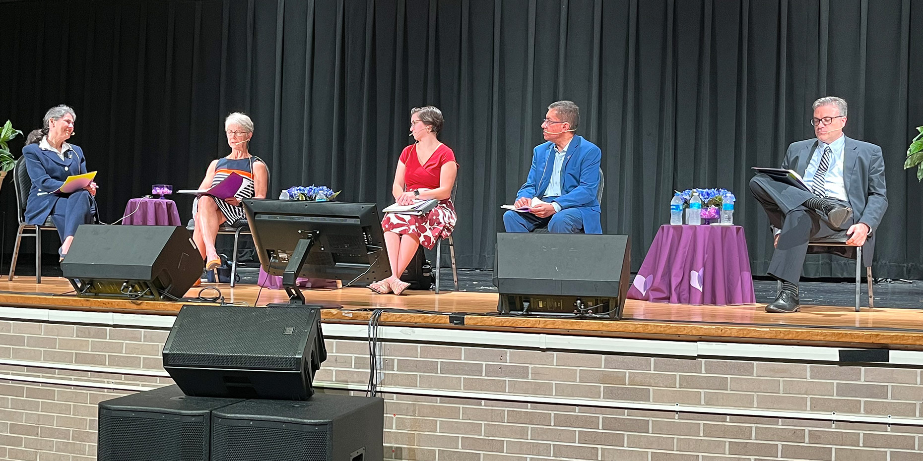 Panelists and moderator sit along stage with microphones at the Care Source health toledo summit