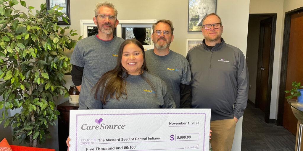 Group of people holding an oversized check looking at the camera and smiling.