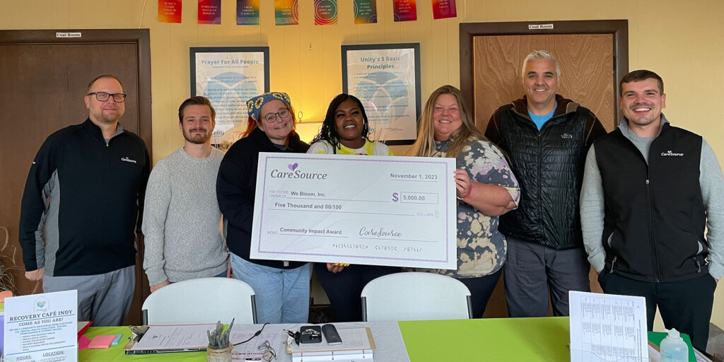 Group of people holding an oversized check looking at the camera and smiling.