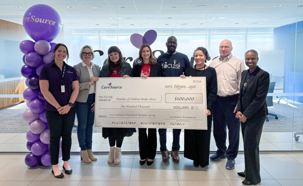 group of people holding large check for $100,000