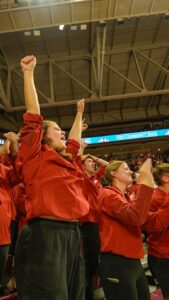 Woman in red shirt raising arms and cheering